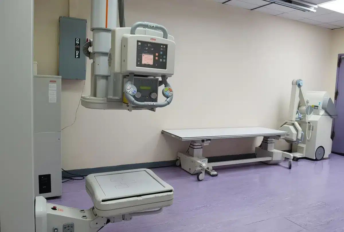 Radiology technician preparing patient for chest X-ray at urgent care clinic in Euless TX