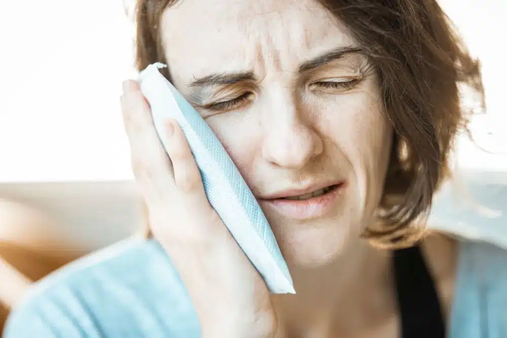 Person applying an ice pack to a swollen ankle joint for home pain relief